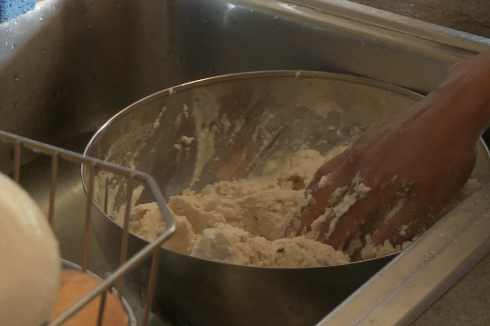 A hand working masa in a metal bowl