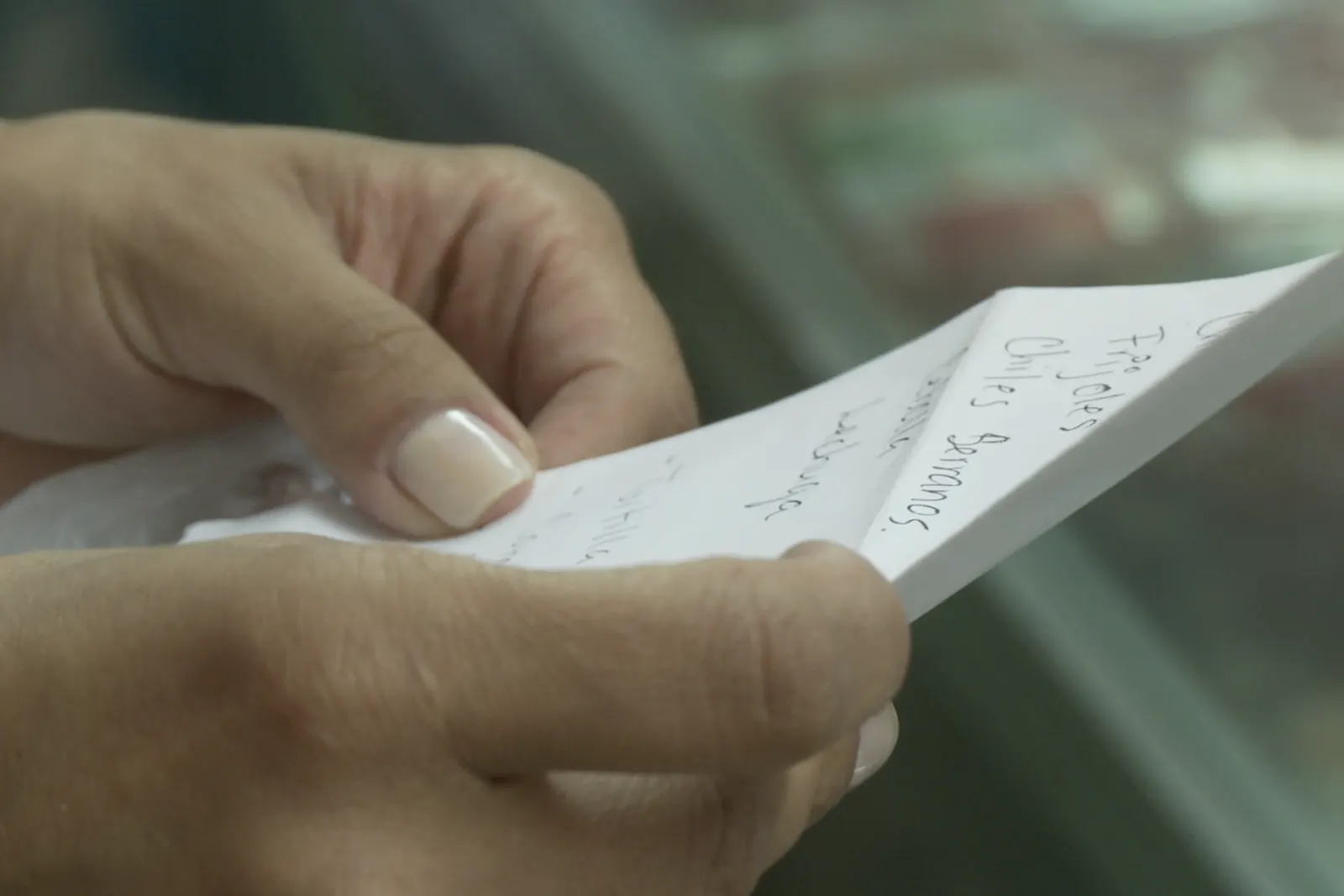 Hands holding a handwritten recipe list